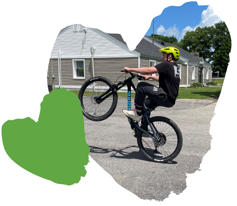 student doing wheelie on bicycle outside of Spaulding residence buildings