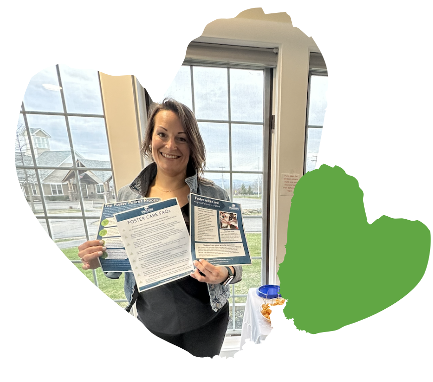 staff member smiling and holding foster care pamphlets