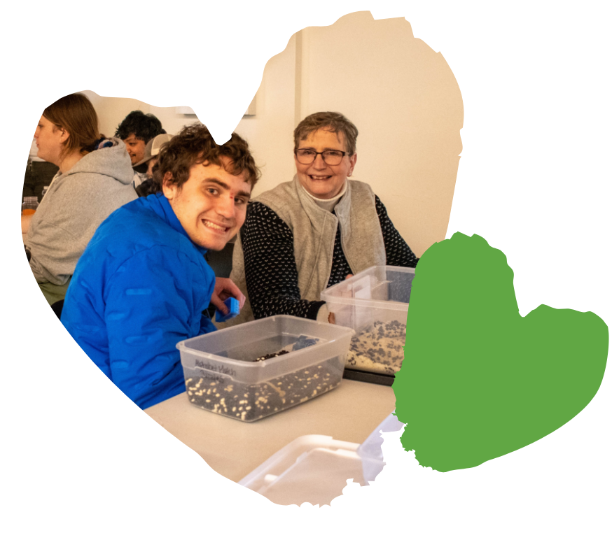 Two people smiling at a table, collaborating on a project with containers of materials.