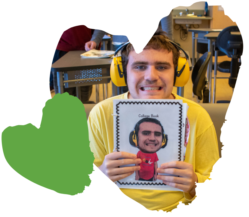 student smiling while showing off collage book he made