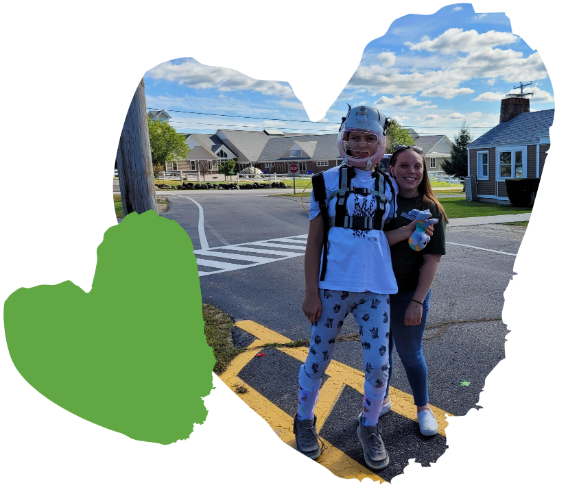 Two people stand on a street, smiling. One wears braces; the sky is partly cloudy. A green heart decorates the image.