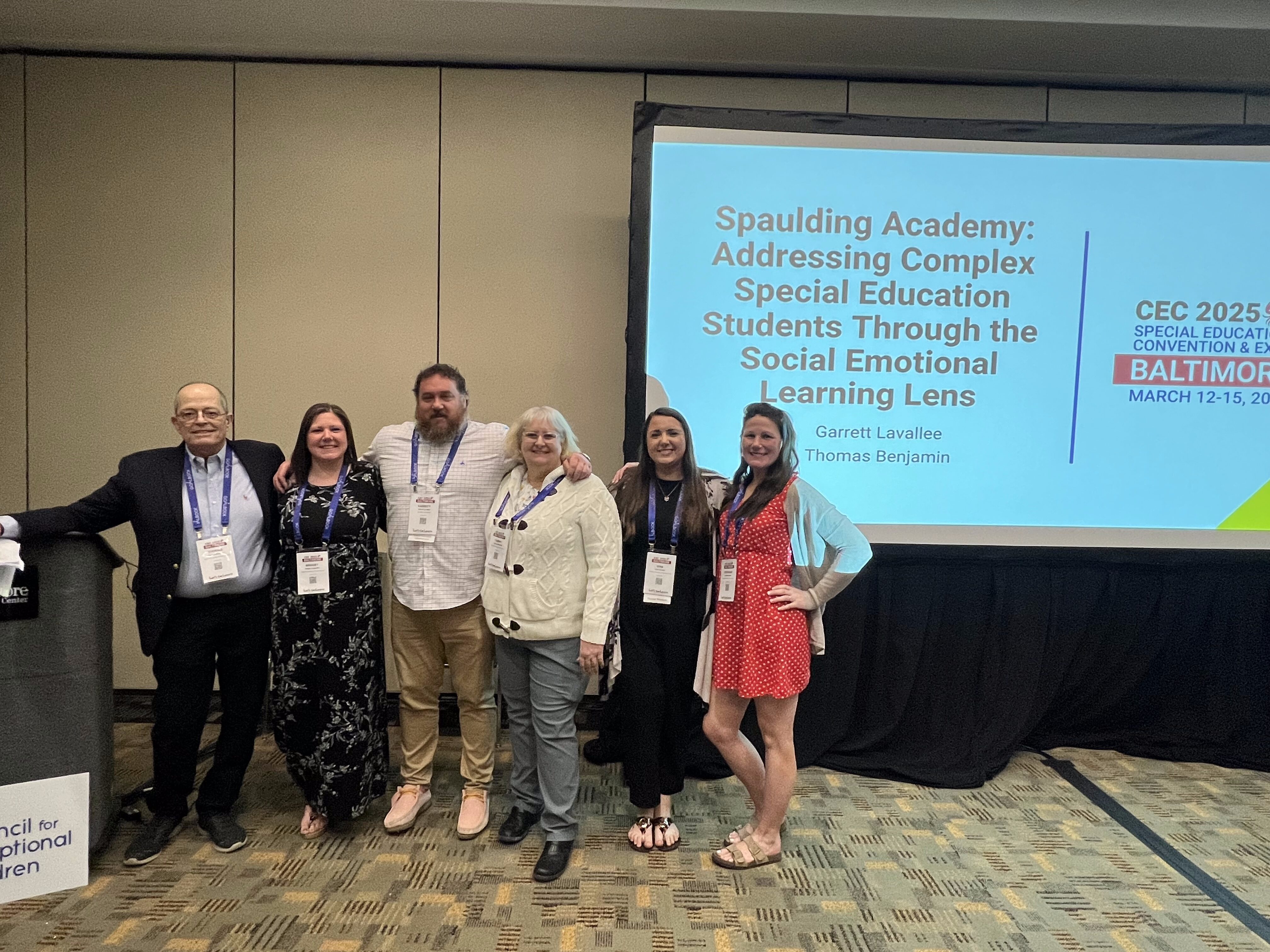 Five people pose in front of a conference screen about social emotional learning for special education students.