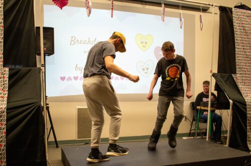 Two boys dancing on a small stage, with a Breakdance slide displayed in the background. Two boys dancing on a small stage, with a Breakdance slide displayed in the background.