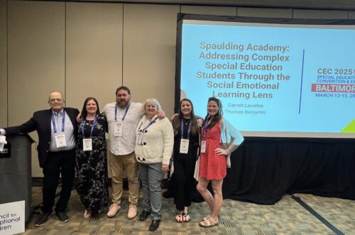 Five people pose in front of a conference screen about social emotional learning for special education students. Five people pose in front of a conference screen about social emotional learning for special education students.