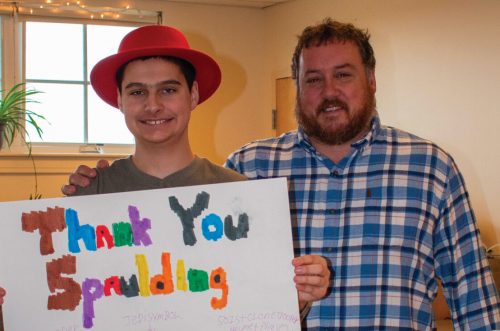 Two people smiling, one holding a colorful thank you poster with Star Wars drawings and messages.